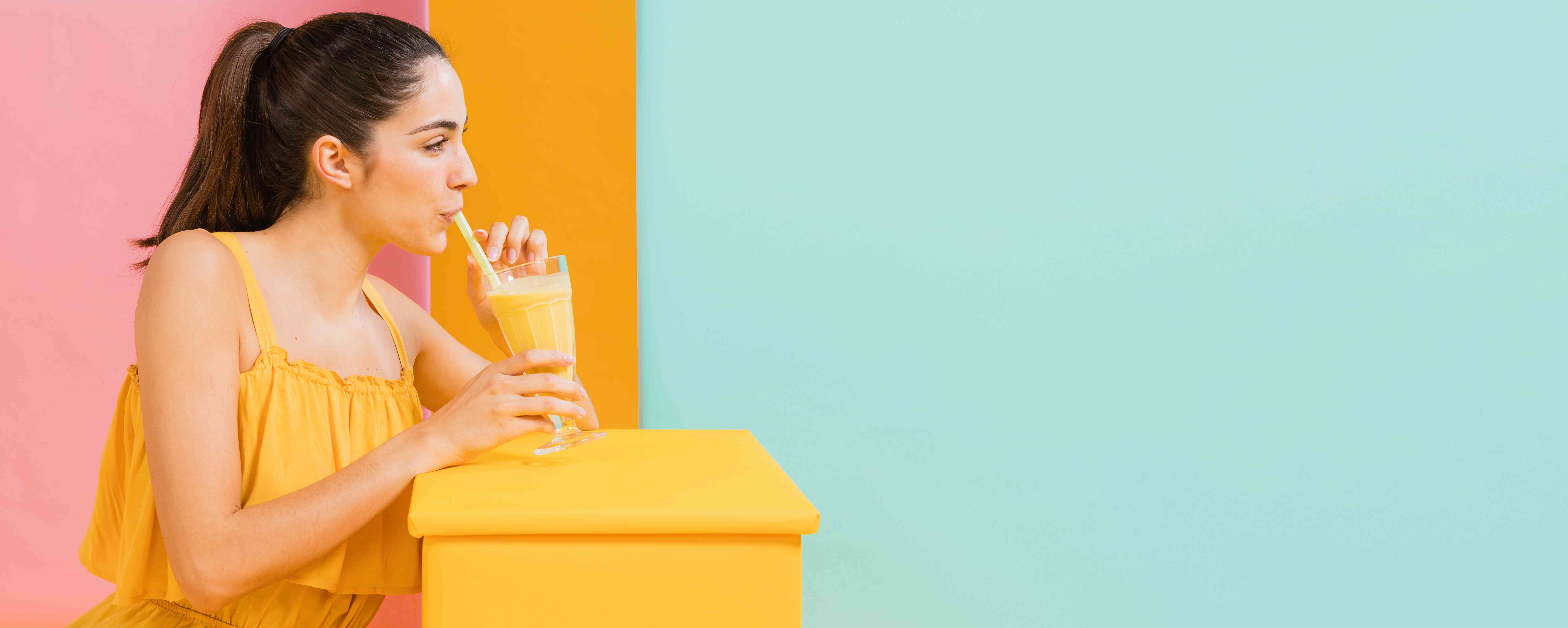 Women wearing a yellow dress drinking juice